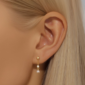Close-up of a gold s925 silver earring with sparkling crystals on a female ear model