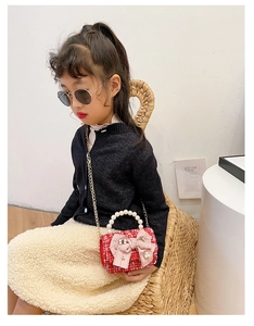 Detail of red tweed girl's bag featuring a pink bow and pearl handle for a princess style