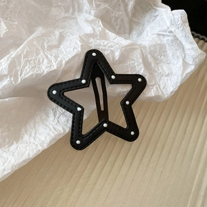 Close-up of star-shaped hair clip with black leather finish and white polka dots pattern