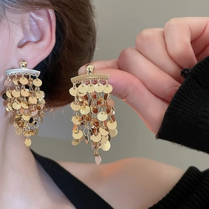 Close-up of gold layered sequin tassel earrings being worn for a stylish look