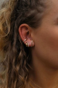 Macro side view of model wearing gold-plated earrings set with cubic zirconia stones