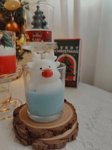 Detail of Christmas reindeer scented candle in glass jar with a natural wooden coaster