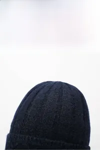 Macro shot of navy blue knitted beanie hat showing soft warm wool textile texture.