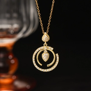 Vue macro du collier doré avec pendentif double cercle et zircon en goutte d'eau