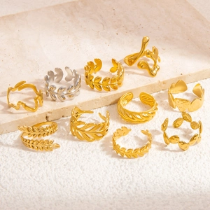 Set of 9 gold and silver leaf-shaped hollow adjustable rings on a textured stone surface