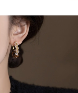 Close-up of vintage hoop earrings with tiger eye stone and crystals on female model