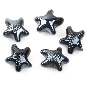 Macro view of five black star-shaped ceramic beads with a shiny polished finish for DIY jewelry