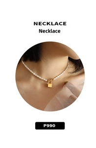 Close-up of pearl necklace with gold padlock pendant and T-bar clasp on female model