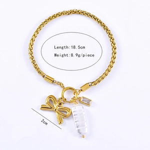 Detailed view of golden bow charm and baroque pearl on a twisted stainless steel bracelet