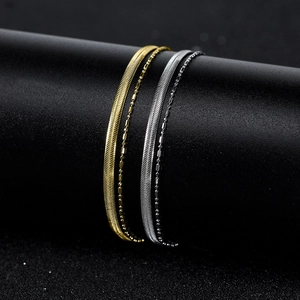 Close-up of gold and silver layered snake chain bracelets on a black display stand