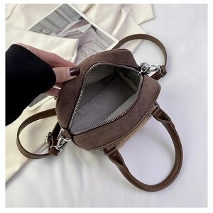 Detail view of the brown faux suede handbag showing the patterned lining and zipper closure