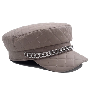 Detail of khaki faux leather newsboy hat with quilted pattern and silver chain decoration