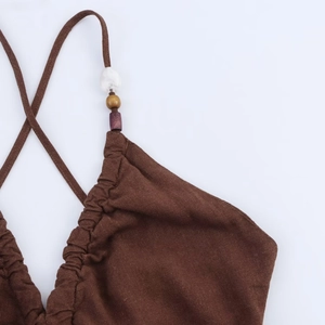 Detailed view of linen blend strap with white and gold bead ornaments on brown dress