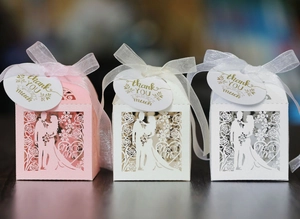 Detailed laser-cut candy boxes in pink, beige, and white with elegant silk ribbons