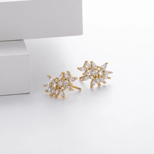 Macro detail of S925 silver snowflake stud earrings with gold plating and clear zircon