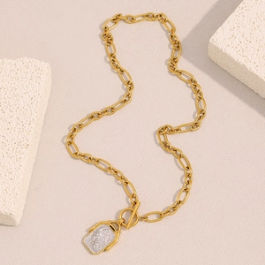 Flat lay of an 18K gold plated moon square pendant necklace on a beige textured stone