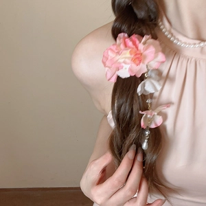 Gros plan d'une pince à cheveux fleur rose en soie avec pompons en perles sur cheveux
