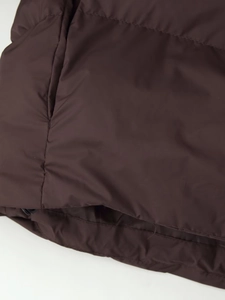Detailed close-up of dark brown padded jacket hem with smooth fabric and stitching