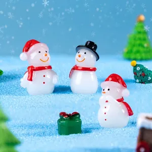 Miniature Christmas snowmen figurines with red scarves on blue sand landscape
