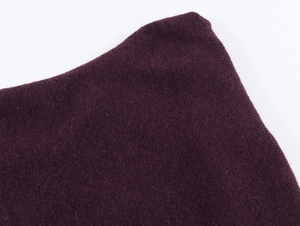 Gros plan sur la texture du tricot violet foncé de ce pull à épaules dénudées