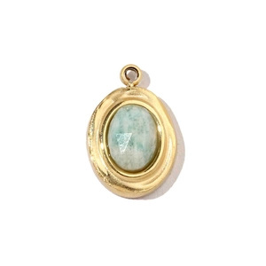 Détail du pendentif ovale doré avec pierre naturelle vert clair et anneau de fixation