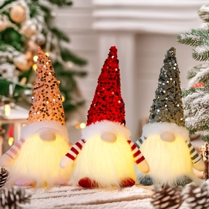 Close-up of three glowing Christmas gnomes with sequin hats and warm LED lights