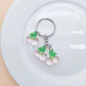 Close-up of pink translucent cherry pendants with green leaves on silver keychain