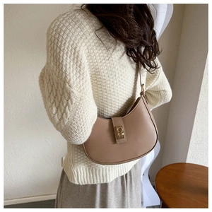 Detail view of khaki hobo bag with gold metal buckle shown on a model in knitwear