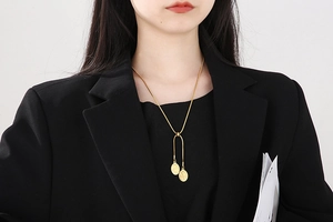 Detail of gold snake chain necklace featuring double oval goddess relief coin pendants