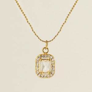 Close-up of golden rectangular zircon pendant with sparkling rhinestones on woven chain