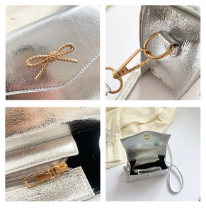 Vue détaillée du mini sac bandoulière argenté avec nœud doré et ferrures en gros plan