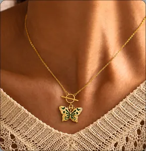 Dettaglio della collana d'oro con ciondolo a farfalla in smalto verde e chiusura a T