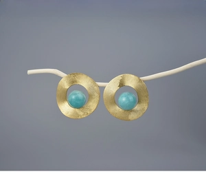 Detail of silver S925 geometric earrings with matte gold finish and sky blue stone