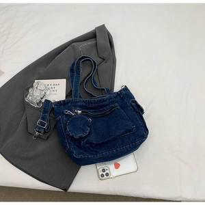 Detail of blue denim tote bag with front zipper pocket and round small coin purse charm