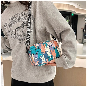 Close-up of cute cartoon rabbit crossbody bag with wide lettered nylon strap on model