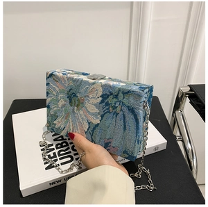 Detailed view of floral jacquard box bag with silver chain and elegant flower patterns