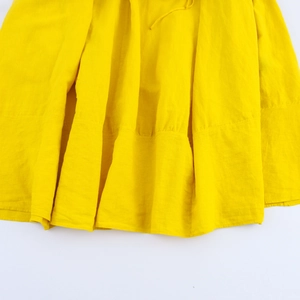 Detail of yellow linen blend dress showing pleated texture and breathable fabric