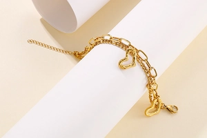 Détail du bracelet multicouche en acier doré avec pendentifs en cœur et fermoir homard