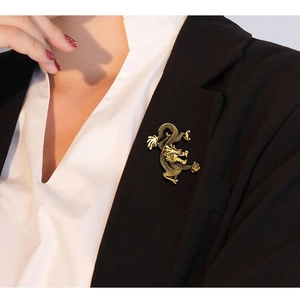 Gros plan d'une broche dragon dorée épinglée sur le revers d'un costume noir élégant