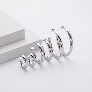 Detail view of four sizes of S925 sterling silver C-shaped hoop earrings on white steps