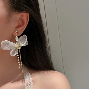 Detailed view of butterfly mesh earrings with long pearl tassels worn by a model