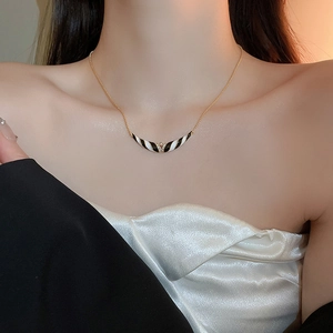 Nahaufnahme einer Goldkette mit einem schwarz-weiß gestreiften Emaille-Anhänger mit Zirkon