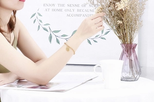 Close-up of a gold Hamsa hand charm bracelet on a woman wrist in a cozy setting
