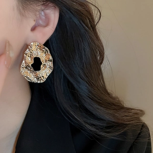 Close-up of irregular gold textured earrings with wrinkled metal finish on a female model