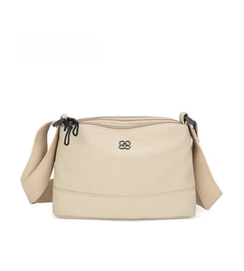 Détail d'un sac à bandoulière beige à trois fermetures éclair et logo trèfle en métal