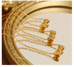 Vue détaillée de colliers dorés avec nœud en cristaux sur un miroir de style vintage