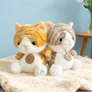 Cute lifelike plush cat dolls with fluffy fur and blue eyes on a soft white rug