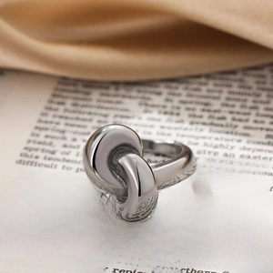 Macro shot of silver knot ring with polished double-loop design on open book pages
