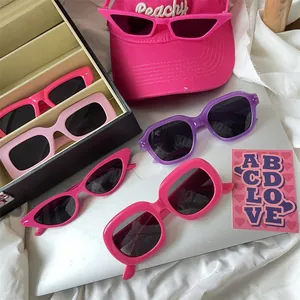 Close-up of trendy thick frame sunglasses in pink and purple colors on a desk