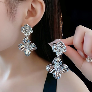 Detailed view of silver double-layered metal flower earrings worn by a model